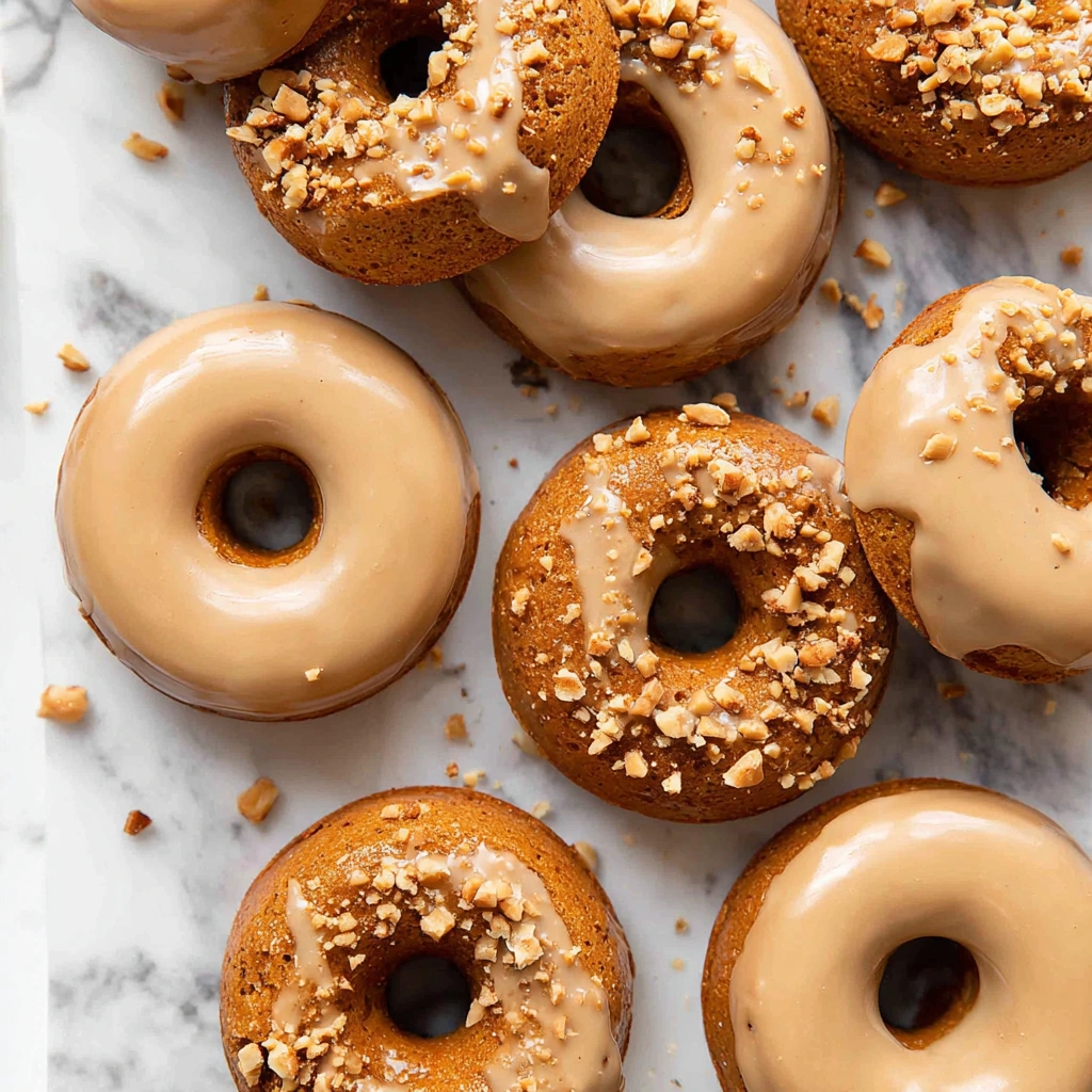 A close-up of a perfectly baked pumpkin donut, topped with a sweet glaze and cinnamon.